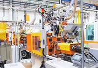 The image shows an industrial setting with machinery and robotic arms, possibly an automated assembly line in a manufacturing plant.