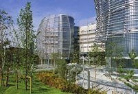 Modern architectural buildings with glass facades surrounded by landscaped greenery and pathways.